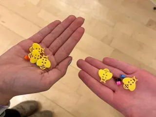 Children's bee buttons for clothing in bright yellow held in both hands for sewing crafts